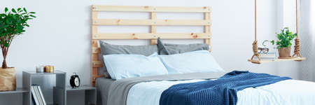 Wooden bed and blue bedding in cozy modern bedroomの写真素材