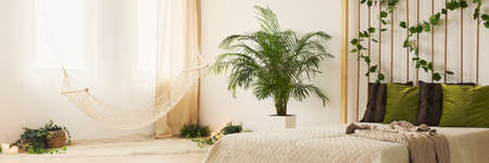 Cozy white and green bedroom with hammock by the window
