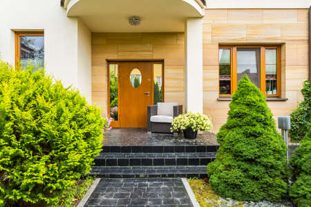 Stylish front entrance to the modern family house with spruces next to cobblestoned pathwayの写真素材