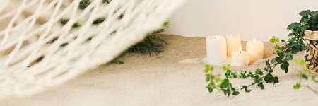 Close-up of sand and candles by white hammock in cozy bedroomの写真素材