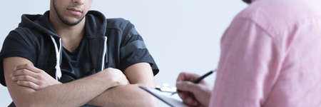 Racial abused teen boy having conversation with psychotherapist