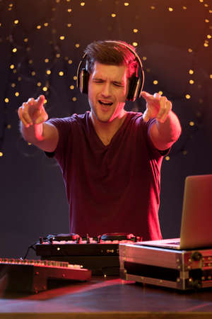 Young DJ singing and playing with headphones on