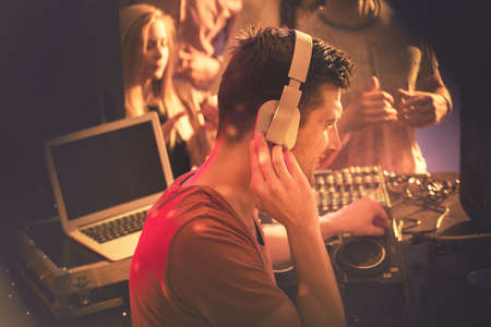 Young handsome DJ playing at the party