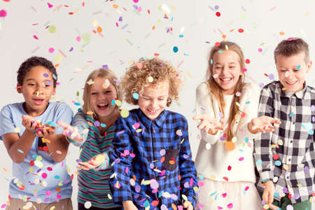 Group of sweet young kids catching colorful confettiの写真素材