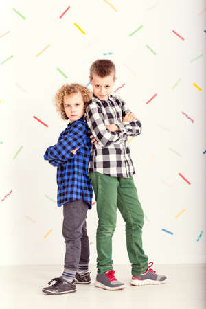 Two young boys standing back-to-back with serious faces