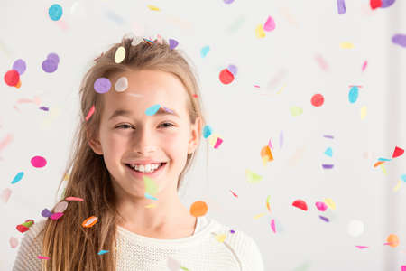Cute little girl smiling with confetti falling downの写真素材