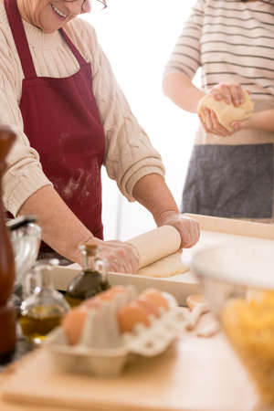 Happy, senior woman rolling dough for pastaの写真素材