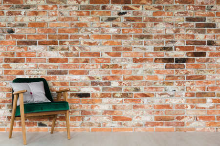 Green, velvet, vintage armchair on brick wall