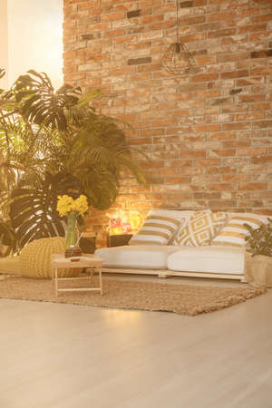 Big green plants and red brick wall in cozy loungeの写真素材