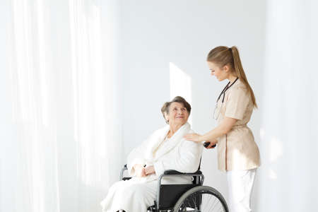 Senior lady in robe sitting in a wheelchairの写真素材