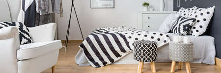 Modern functional black and white bedroom with armchair and bed
