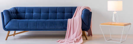 Blue sofa and small wooden table with a lamp in white living roomの写真素材