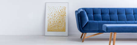Yellow poster, blue sofa and table in white living room