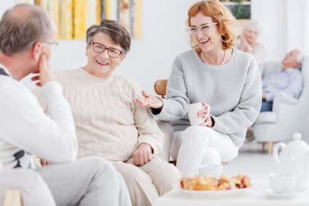 Senior happy women and older man gossiping at a tea party