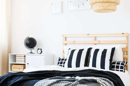 Black and white decor of stylish bedroom with wooden bedの写真素材