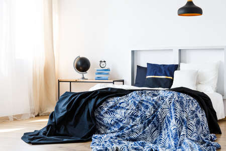 Bed with blue and white bedding and modern headboardの写真素材