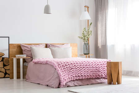 White and pink design of cozy bedroom with wooden bedの写真素材