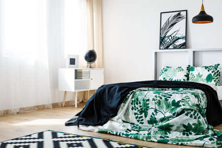 White and green bedding with plant design on comfortable white bedの写真素材