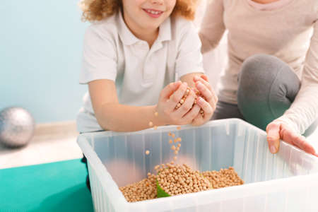 Boy playing with chickpeas during his sensory integration therapyの写真素材