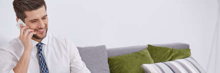 Man doing phone conversation sitting on a couchの写真素材