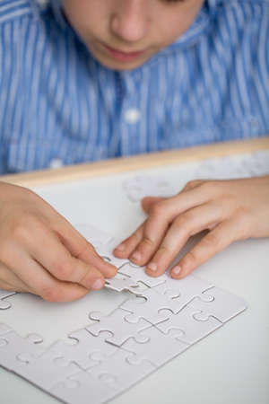 Focused boy solving a puzzle on a tableの写真素材