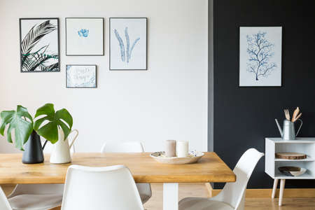Black and white dining room with wooden table and postersの写真素材