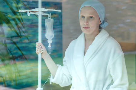 Young sad woman standing with drip at the hospital