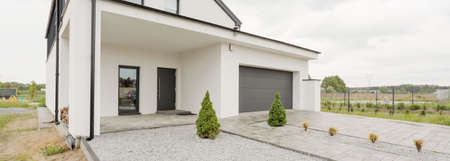 Big concrete white modern house with long drive to car garage and big gardenの写真素材