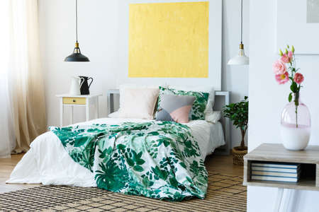 Yellow abstract painting above the bed in stylish bedroom