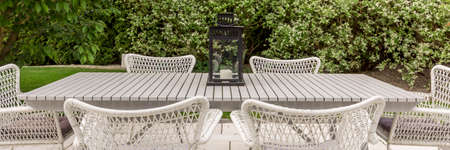 Terrace in the backyard garden with white patio chairs and tableの写真素材