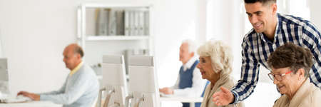 Young IT teacher explaining internet to happy elderly womanの写真素材