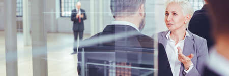 Mature businesswoman with investor talking in industrial interior, panorama