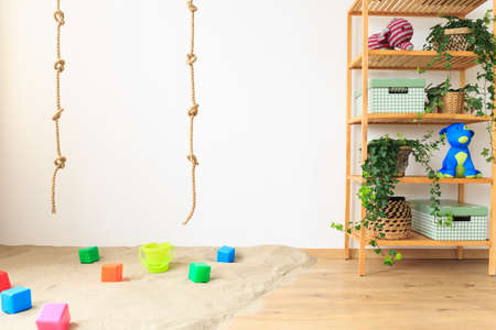 Rope, sand with toys, and wooden shelf in baby roomの写真素材
