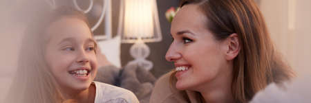 Happy growing up girl talking with her young motherの写真素材