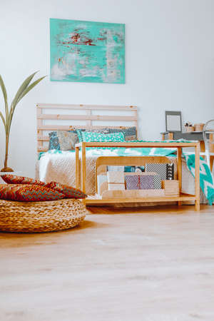 Blue modern painting hanging on the white wall above the wooden bed