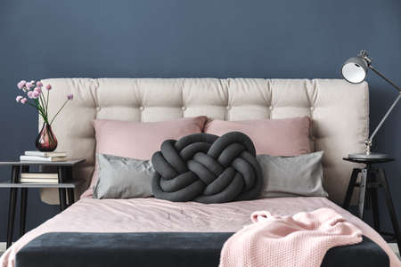 Vase with fresh pink flowers standing on books on bedside tableの写真素材