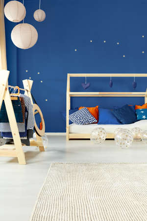 Blue decorated room with minimalist bed and wooden coat rackの写真素材