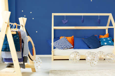 Simple coat rack and wooden decorated bed in modern colorful roomの写真素材