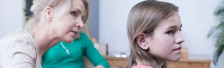 Middle-aged blonde woman talking to young girl during therapyの写真素材