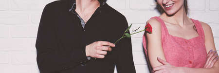 Passionate man touching his woman's arm with a red roseの写真素材