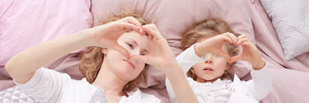 Panorama of woman playing with child in bedの写真素材