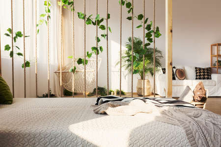 Inspiring rope and ivy decorative room divider next to elegant bed in original apartment