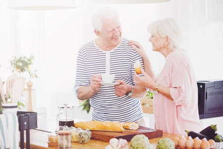 Senior couple eating breakfast together in the kitchenの写真素材