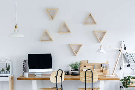 Scandinavian study workspace with computer, wooden desk and white wall