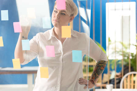 Corporate woman placing sticky notes on a glassboard