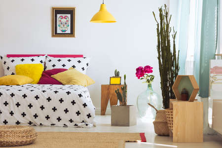 Bright unique bedroom with plants, rug, poster and colorful pillowsの写真素材