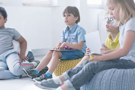 Boy sits in a multicultural group of children and takes part in computer science classesの写真素材