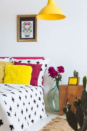 Bedroom with cross duvet, yellow lamp and sugar skull posterの写真素材