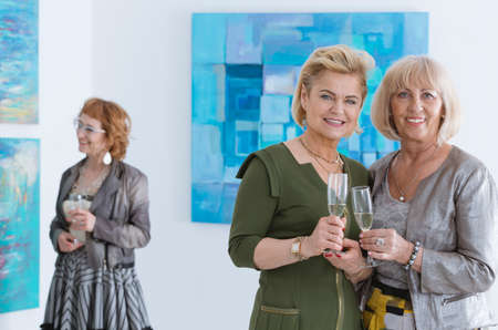 Photo of two elegant senior ladies smiling and holding glassesの写真素材