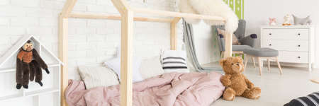 Modern wooden bed in house shape in cozy baby roomの写真素材